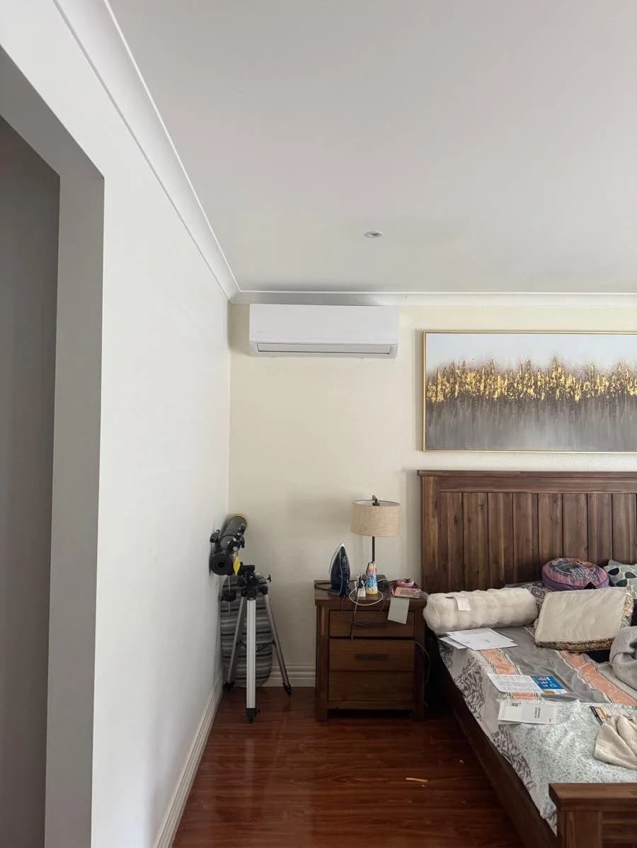 Wall-mounted indoor air-conditioning unit professionally installed in a Victorian bedroom